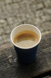 Small cup of coffee made out of paper sitting on a wooden counter top